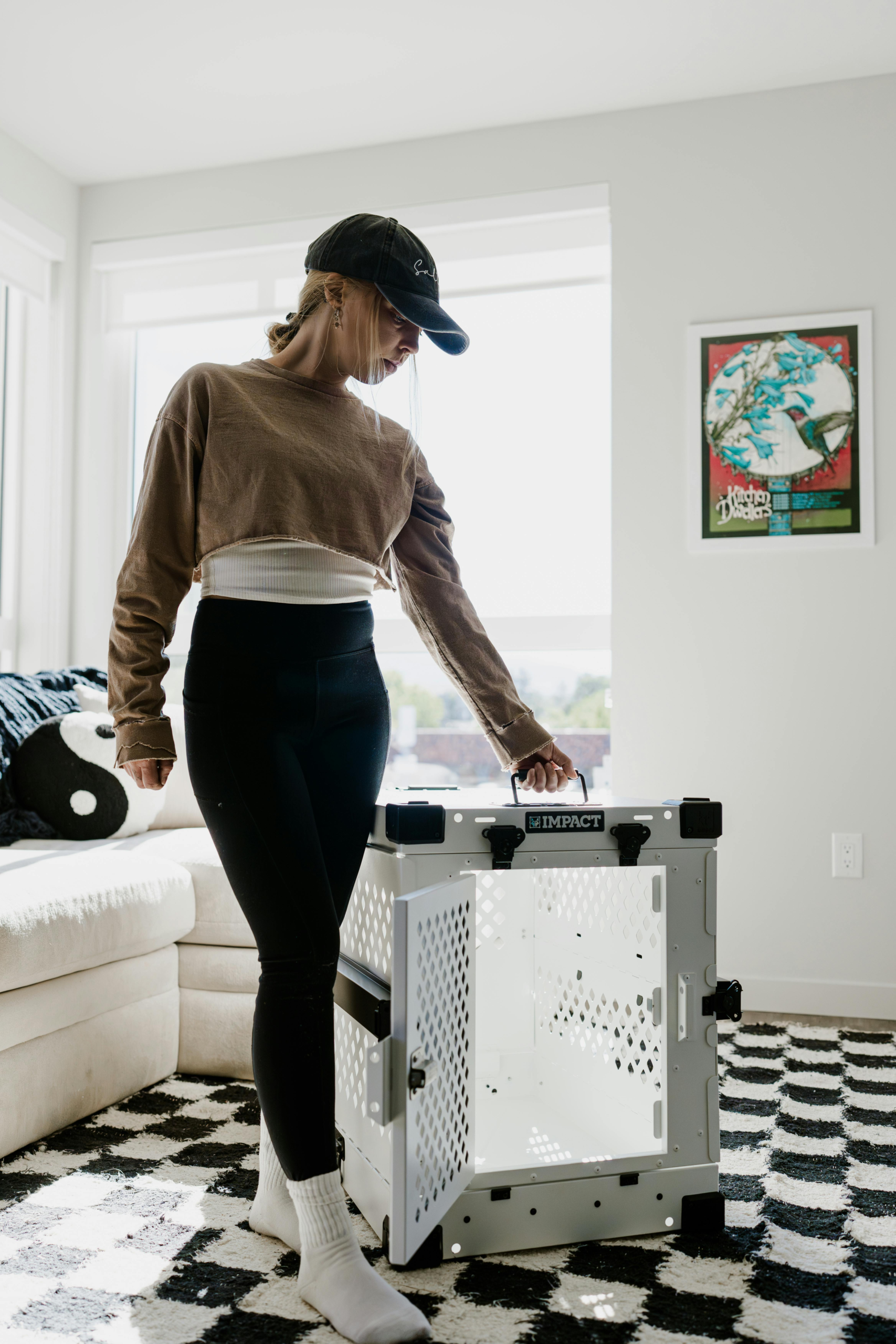 Woman standing next to a dog crate in a modern living room setting.